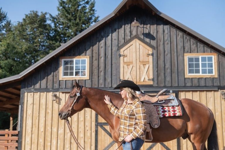 Brandi Coplen with a saddled horse in front of a barn on a Whatcom County horse property